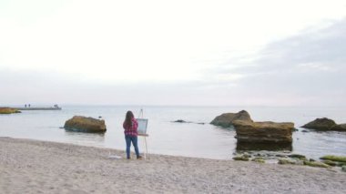 Sahilde deniz boyayan kadın.