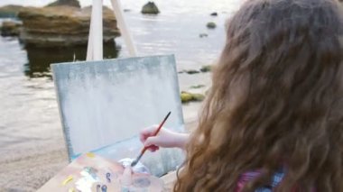 Sahilde deniz boyayan kadın.