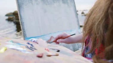 Sahilde deniz boyayan kadın.