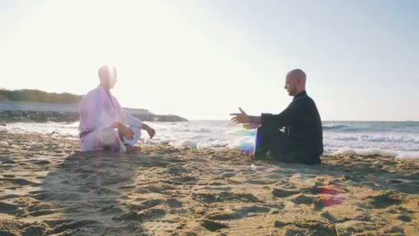 两个年轻男子在沙滩上沉思日落 免版税图库视频片段