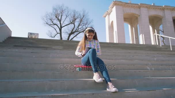 Girl on stairs listening music — Stock Video
