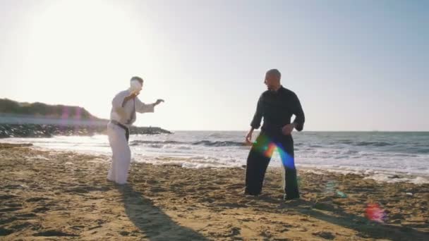 Karate strijders vechten op strand — Stockvideo