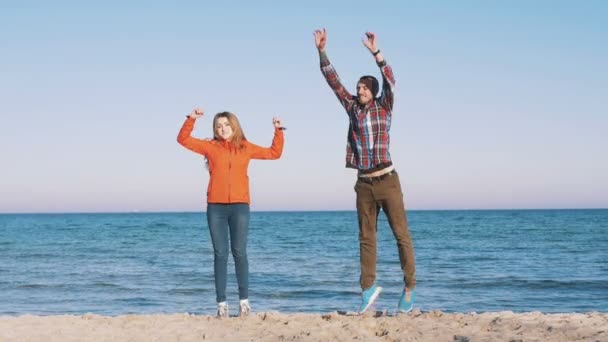 Пара, прыгающая на берегу моря — стоковое видео