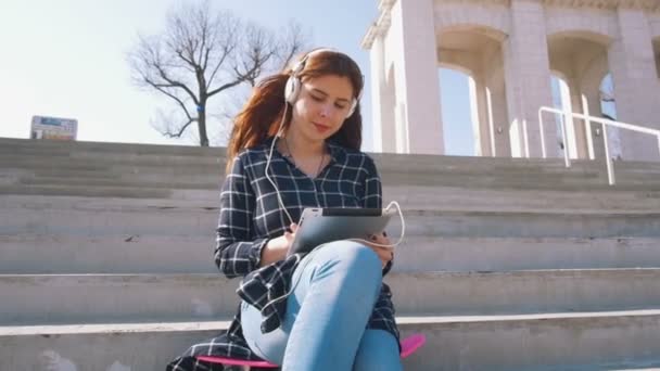 Girl on stairs listening music — Stock Video