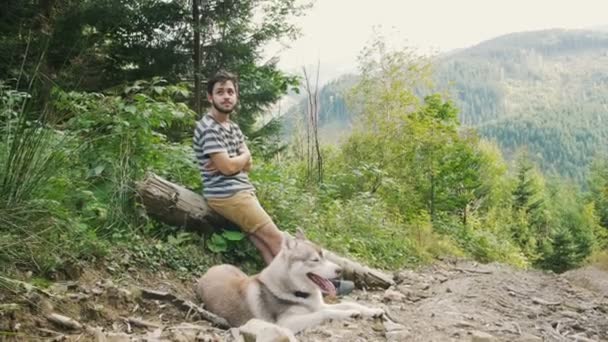 Hombre con perro husky en el bosque — Vídeo de stock