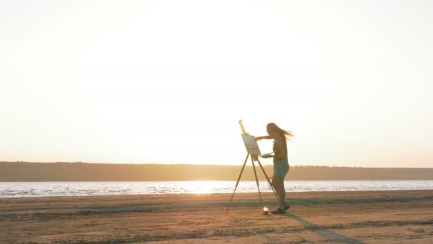 Female artist painting on beach — Stock Video