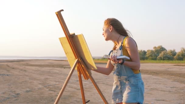 Female artist painting on beach — Stock Video