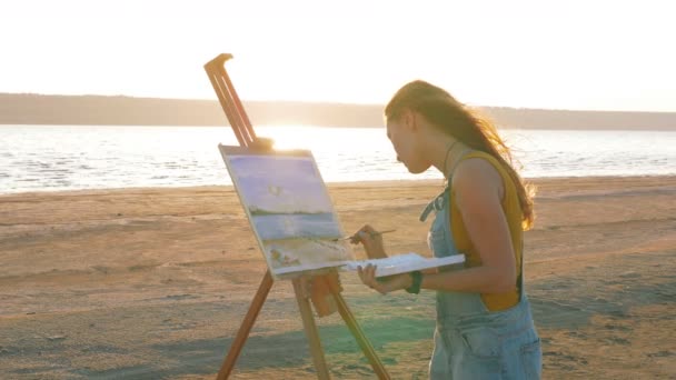 Kvinnlig konstnär målar på stranden — Stockvideo