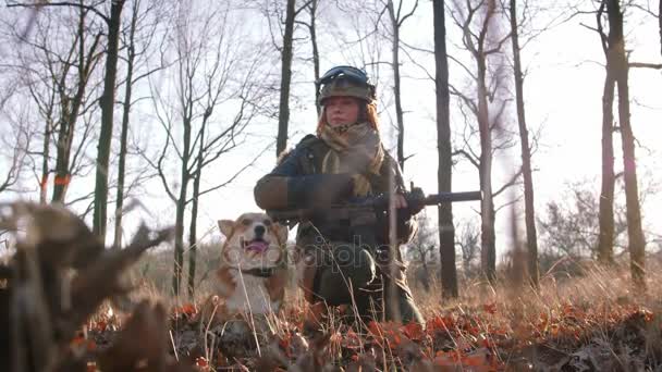 在秋天森林戏剧与狗的妇女在保护制服与枪 免版税图库视频
