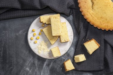 Yuvarlak ahşap bir tahtanın üzerinde taze pişmiş mısır ekmeği ve siyah peçeteli koyu bir arka planda mısır. Amerikan ulusal mutfağında geleneksel hamur işleri. Uzayı kopyala Üst görünüm