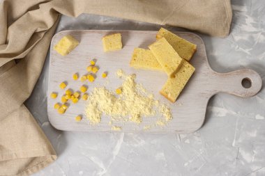 Tahta beyaz bir tahtanın üzerinde taze pişmiş mısır ekmeği ve beyaz bir zemin üzerinde un. Amerikan ulusal mutfağında geleneksel hamur işleri. Üst görünüm