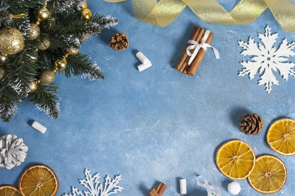 Рождественская композиция Рамка рождественских украшений из конусов, корицы, оранжевых ломтиков и елки на синем фоне. Рождество, зима, новый год. Плоская кладка, вид сверху, копировальное пространство — стоковое фото