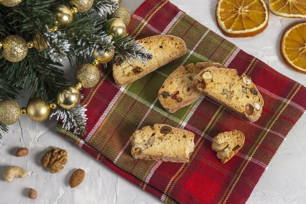 Традиционные итальянские печенье Biscotti или Cantuccini с фундуком, миндаль, грецкие орехи на красно-зеленой салфетке рядом с елкой. Рождество и Новый год выпечки. Вид сверху — стоковое фото