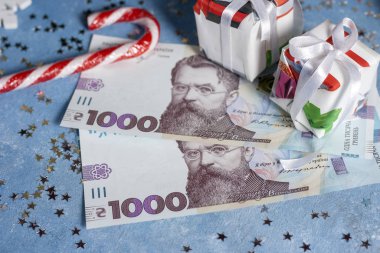 Yıldızlı, şekerli ve hediyeli mavi bir arka planda Ukrayna 1000 Hryvnia 'sı. Ukrayna 'da Noel ve Yeni Yıl hediyeleri alma kavramı