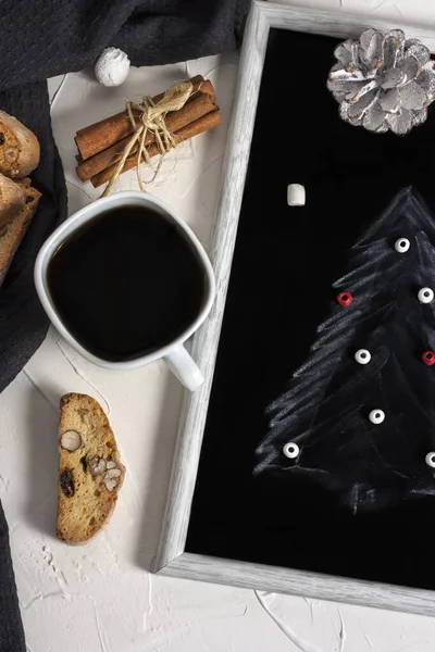Зимняя рождественская композиция. Чашка кофе на столе с печеньем Bisconti, корицей и черной доской с рисунком елки. Рождественское настроение. Концепция макета. Вид сверху — стоковое фото