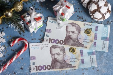 Yıldızlar, hediyeler, kar taneleri, şekerler ve Noel ağacı olan mavi bir arka planda Ukrayna 1000 Hryvnia 'sı. Ukrayna 'da Noel ve Yeni Yıl hediyeleri alma kavramı