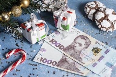 Yıldızlar, hediyeler, kar taneleri, şekerler ve Noel ağacı olan mavi bir arka planda Ukrayna 1000 Hryvnia 'sı. Ukrayna 'da Noel ve Yeni Yıl hediyeleri alma kavramı