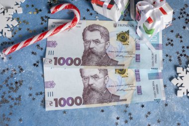 Yıldızlar, hediyeler, kar taneleri, şekerler ve Noel ağacı olan mavi bir arka planda Ukrayna 1000 Hryvnia 'sı. Ukrayna 'da Noel ve Yeni Yıl hediyeleri alma kavramı