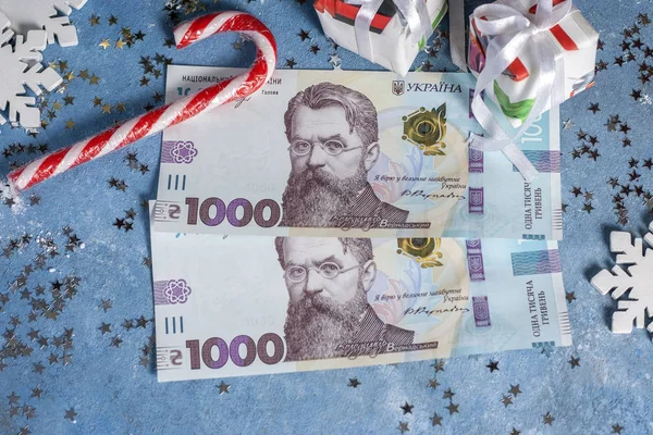Ukrainische 1000 Griwna auf blauem Hintergrund mit Sternen, Geschenken, Schneeflocken, Süßigkeiten und Weihnachtsbaum. das Konzept des Kaufs von Weihnachts- und Neujahrsgeschenken in der Ukraine — Stockfoto