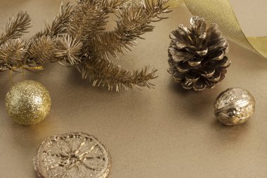 Noel veya Yeni Yıl kompozisyonu. Oyuncak, çam kozalağı ve kurutulmuş turuncu dilimli altın rengi bir Noel ağacı dalı. Tebrik kartı ya da davetiye için bayram ve kutlama kavramı