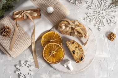 Tarçın çubukları, bir köknar dalının yanında bej bir peçetede kurutulmuş portakal dilimleri, çam kozalağı, fındık, kar taneleri ve marşmelov ile bağlanır. Noel konsepti. Üst görünüm