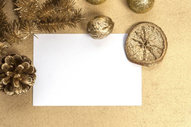 Noel veya Yeni Yıl kompozisyonu. Beyaz bir kağıt parçasının etrafında bir oyuncak, bir yumru ve bir dilim altın rengi portakal olan Noel ağacı dalıyla. Tebrik kartı için bayram ve kutlama kavramı.