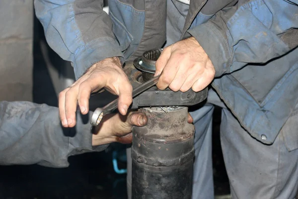 stock image Truck repair. Two mechanics in work clothes are repairing wagon crankshaft with tools.