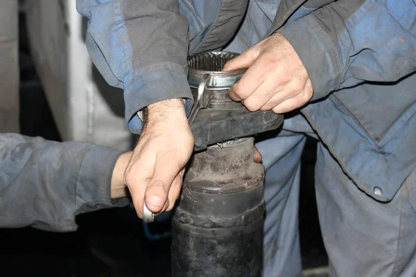 Truck repair. Two mechanics in work clothes are repairing wagon crankshaft with tools.