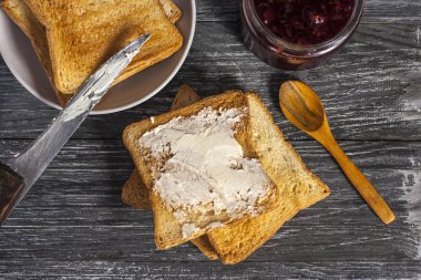 Lezzetli bir kahvaltı için malzemeler. Tereyağlı kızarmış ekmek ve ahududu reçeli ahşap bir masada.
