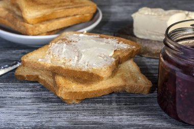 Lezzetli bir kahvaltı için malzemeler. Tereyağlı kızarmış ekmek ve ahududu reçeli ahşap bir masada.