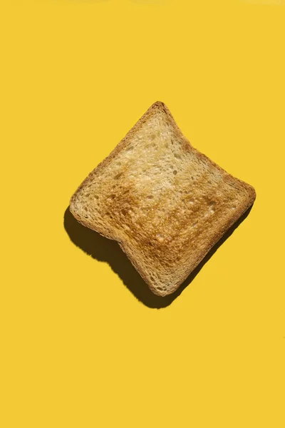 Um pedaço de ouro de torrada frita de pão branco em um fundo amarelo brilhante. Espaço de cópia — Fotografia de Stock