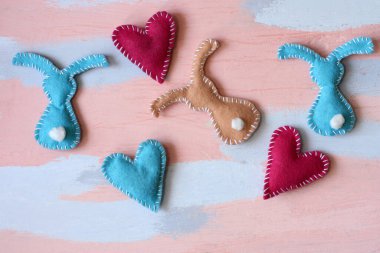 El yapımı çok renkli Paskalya tavşanları ve pembe-mavi arka planda kalpler. Asgari paskalya konsepti. Üst manzara, düz uzanma.