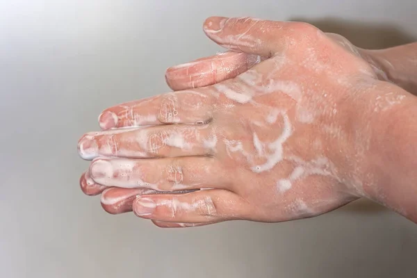 灰色の背景に石鹸泡の若い男の手 手洗いだ 最小限の衛生 ウイルス対策の概念 — ストック写真