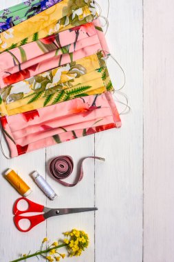 Koronavirüs el dikişlerinden koruyucu tıbbi maskeler üretiliyor. Hafif ahşap arka planda virüsün el yapımı tıbbi maskeleri..