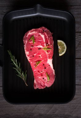 Çiğ et, biberiyeli pişmemiş biftek, limon ve siyah tavada baharat.