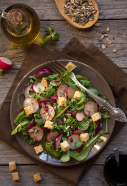 Turplu taze sebze salatası, roka, balzamik sirke ve koyu ahşap üzerine kızarmış ekmek.