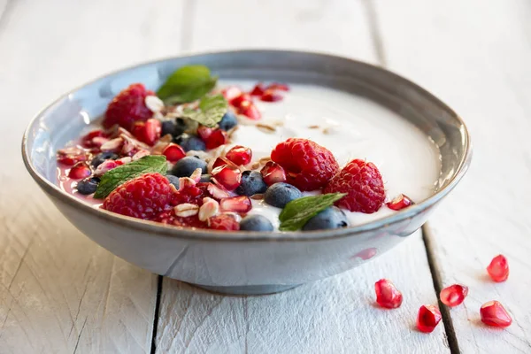 Yogurt with fresh fruit, mint and cereals in a bowl, healthy breakfast
