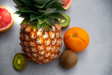 Olgun ananas ve diğer meyveler - portakal, kivi, gri arka planda greyfurt