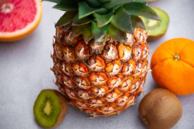 Olgun ananas ve diğer meyveler - portakal, kivi, gri arka planda greyfurt