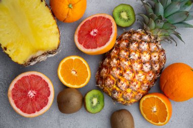 Olgun ananas ve diğer meyveler - portakal, kivi, gri arka planda greyfurt