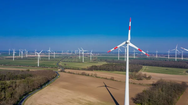 Zeestow, Brandenburg / Almanya - 26.03.2020: Brandenburg 'da bir rüzgar çiftliği, tarlalar ve çayırlar üzerinde güneş ışığı altında birçok rüzgar türbini etrafa saçılmış durumda..