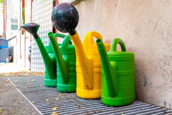 Vier Gebrauchte Gartengießkannen Grün Und Gelb Stehen Auf Einem Gitter — Stockfoto