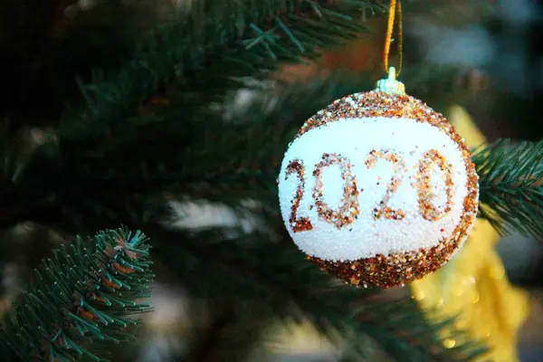 Новогодний Золотой бал с белой вставкой и надписью 2020 года на фоне ветвей искусственной зеленой елки — стоковое фото
