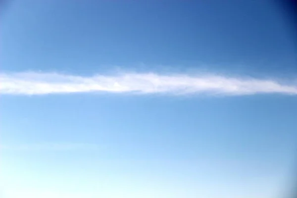 Spring blue sky with a thin strip of clouds. bright blue sky and a band of clouds horizontally. — 스톡 사진