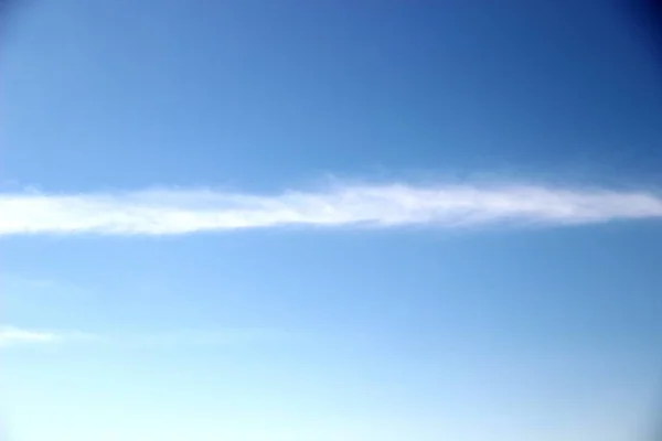 Cielo azul brillante con una tira estrecha blanca de nubes de plumas. cielo azul brillante con una ligera niebla de nubes de plumas —  Fotos de Stock