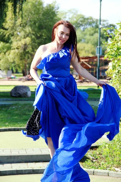 Mujer en un vestido azul largo que revoloteaba en el viento. verticalmente — Foto de Stock