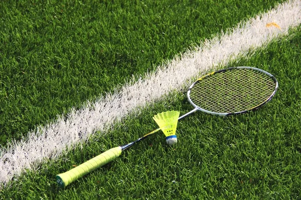 badminton racket, yellow plastic training shuttlecock on the green grass