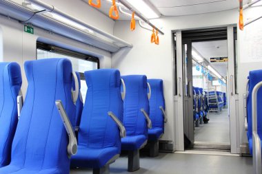 Boş metro vagonu. Elektrikli vagonda boş mavi sandalyeler ve turuncu tırabzanlar, seçici odaklanma