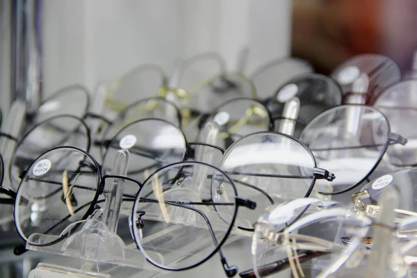 Escaparate de óptica. Muchas gafas para mejorar la visión en una fila . — Foto de Stock