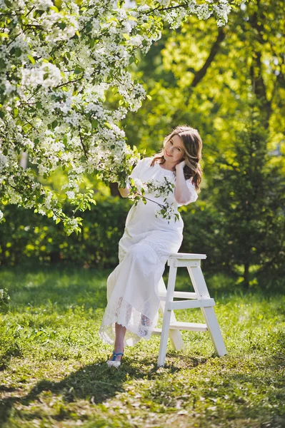 La chica en la posición vestida de blanco descansando en una hermosa —  Fotos de Stock